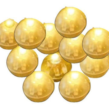 Glänzende, goldene Kapseln in Kugelform, dicht aneinandergereiht auf weißem Hintergrund angeordnet“